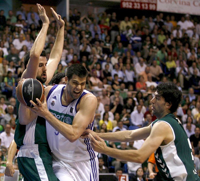 El pívot del Real Madrid Felipe Reyes intenta superar la defensa de los jugadores del Unicaja de Málaga.