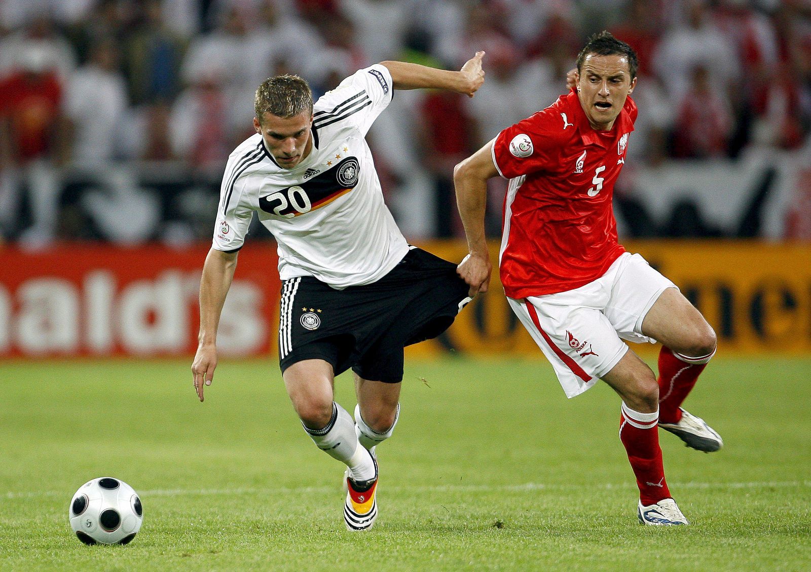 El jugador de la selección polaca de fútbol Dariusz Dudka agarra a Lukas Podolski, goleador de la selección alemana.