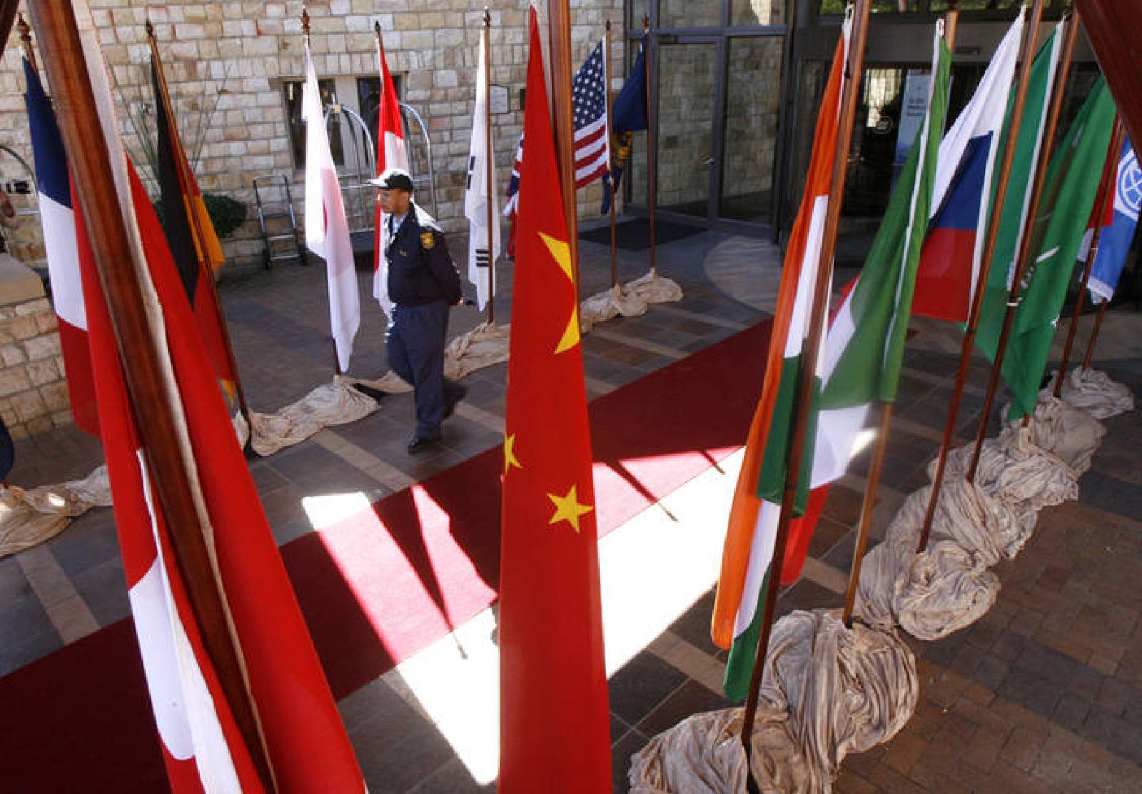 A police officer walks past flags as finance ministers and central bank governors attend opening session of G20 meeting at Kleinmond near Cape Town