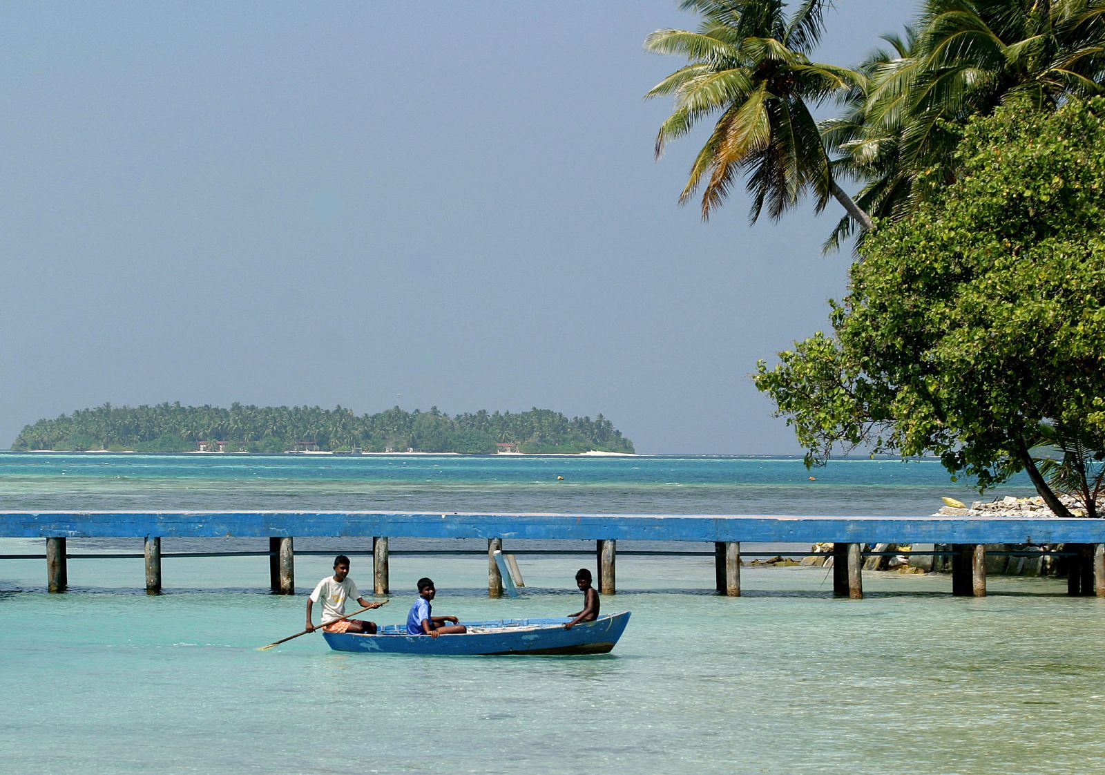 Unos niños reman en la costa de las islas Maldivas.