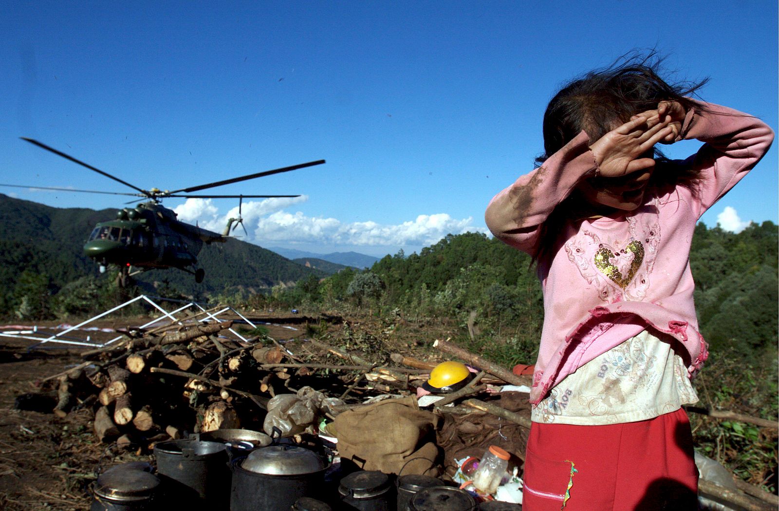 Imagen de una pequeña que espera la ayuda humanitaria que llega en helicópero a Chuxiong (China) por un movimiento de tierras.