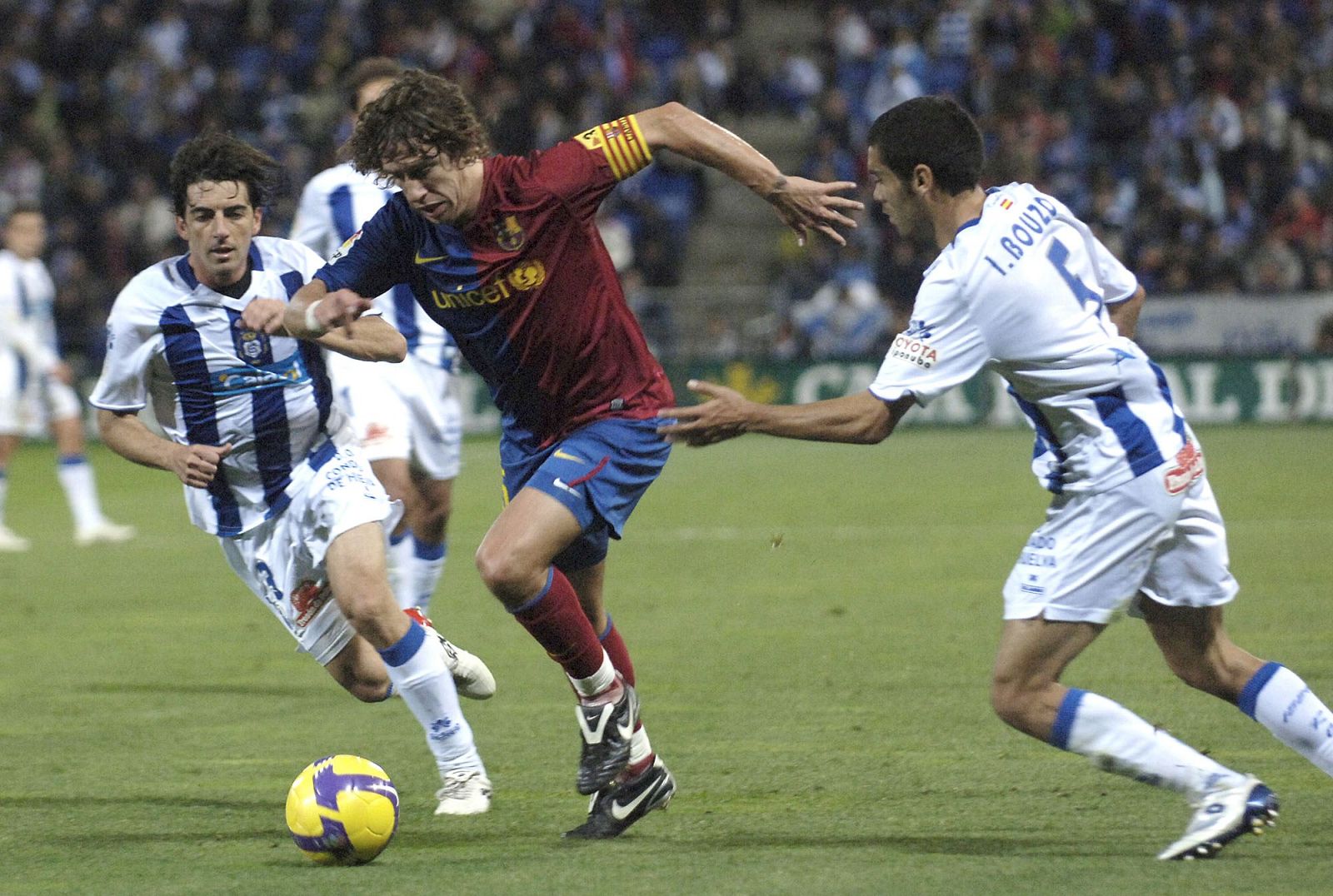 Puyol pelea por un balón entre Bouzón y Javi Guerrero, del Recre.