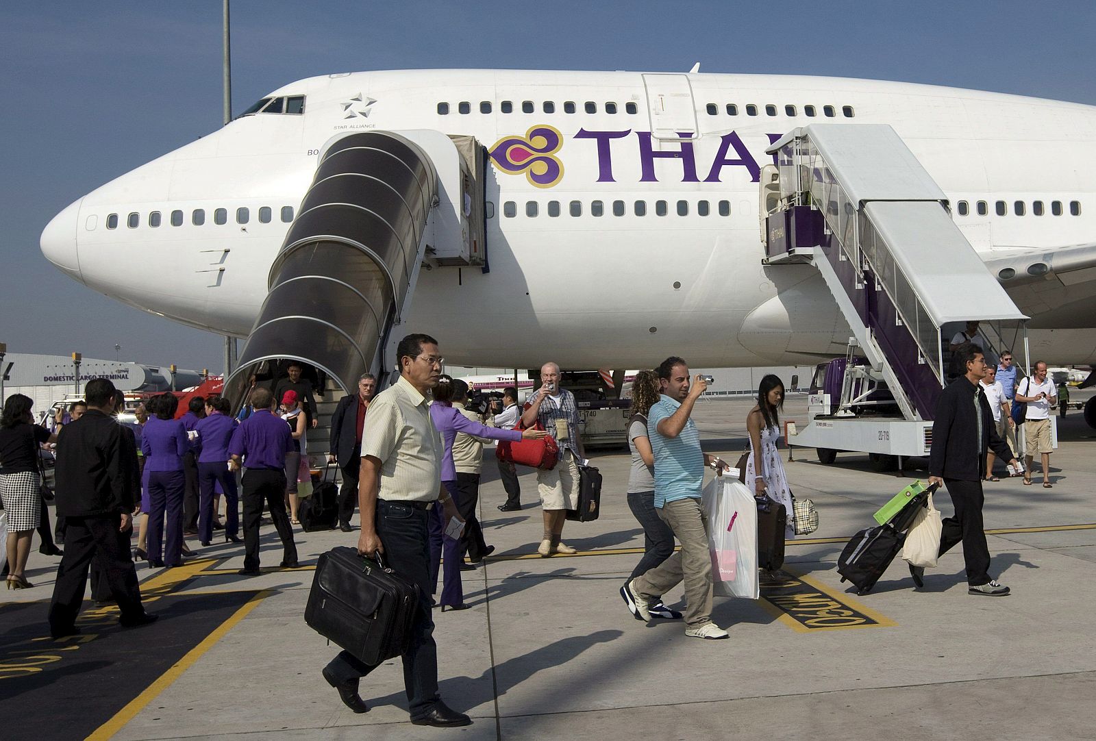 Los pasajeros del primer avión que aterriza en el aeropuerto internacional Suvarnabhumi de Bangkok, descienden de la nave de Thai Airways, después de que los manifestantes de la oposición anunciaran el fin de las protestas.