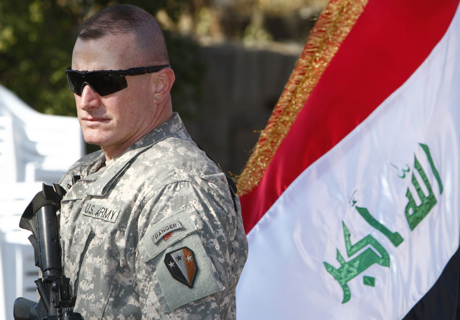 A U.S. soldier stands guard near an Iraqi flag during a handover ceremony of the Green Zone in Baghdad