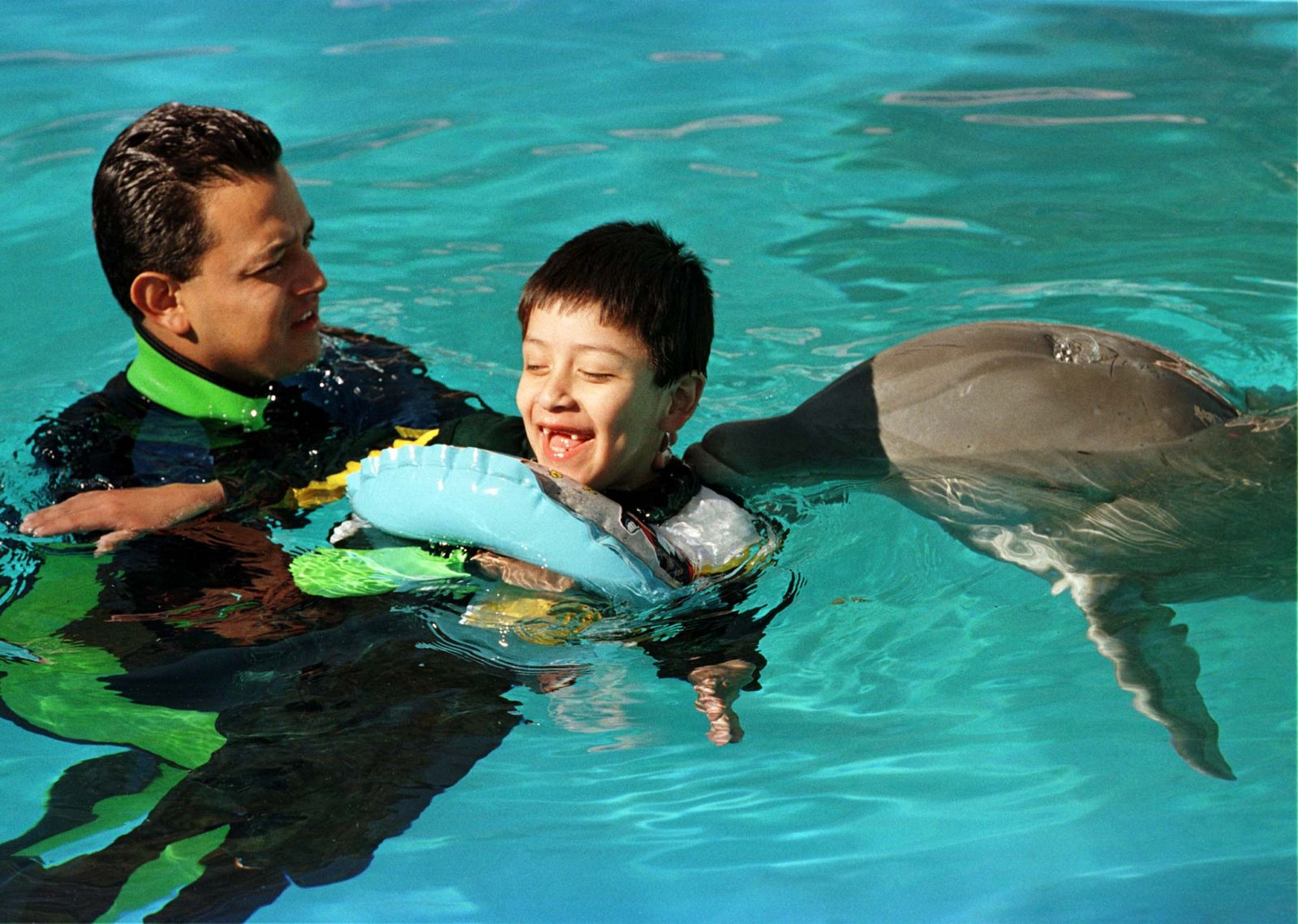 YOUNG HANDICAPED BOY RECEIVES THERAPY FROM A DOLPHIN