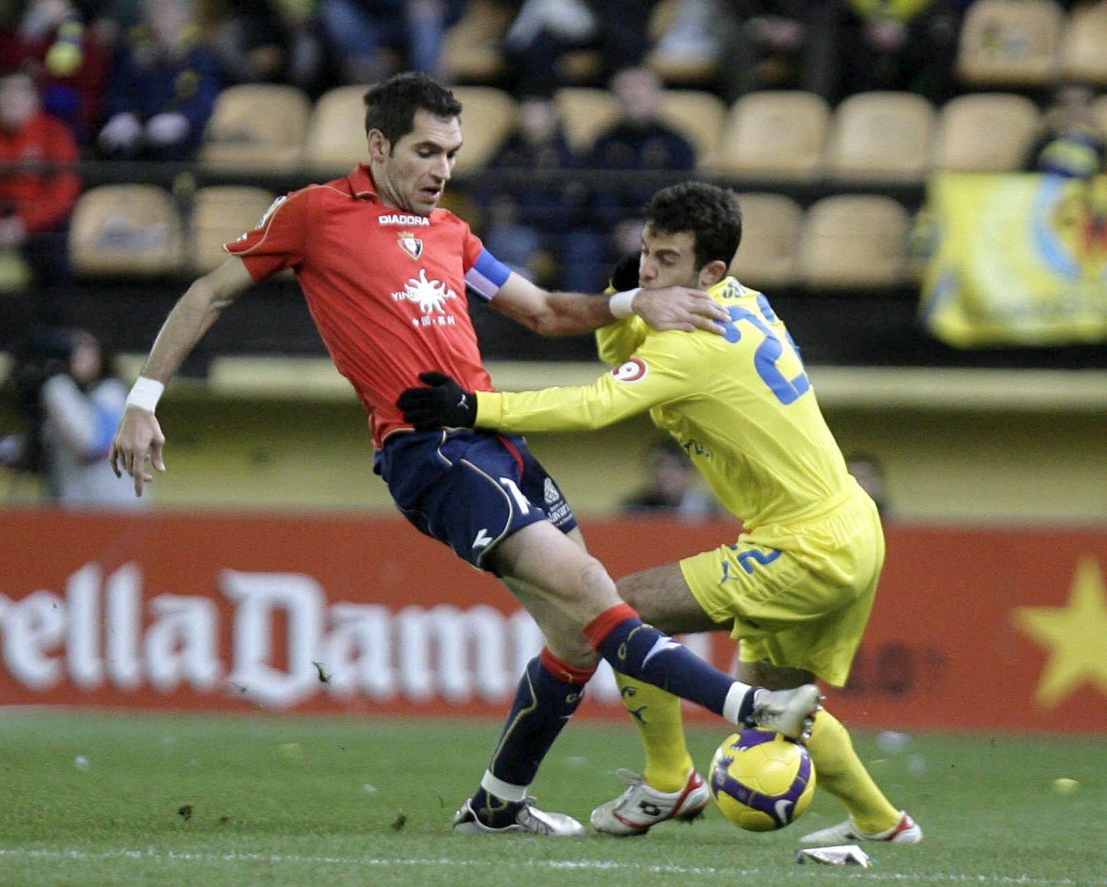 El delantero del Villarreal Rossi (d) y el defensa de Osasuna Miguel Flaño luchan por un balón.