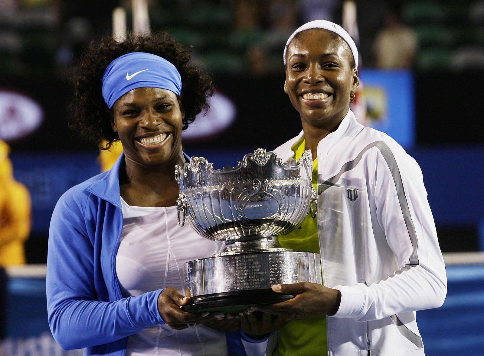 Serena y Venus Williams alzan el trofeo de campeonas en dobles del Open de Australia.