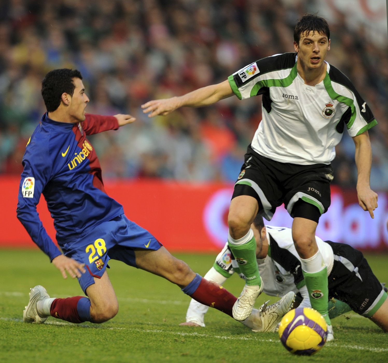 El jugador del Barça, Sergio Busquets, lucha por la posesión de la pelota contra el jugador del Racing, Oriol Lozano.