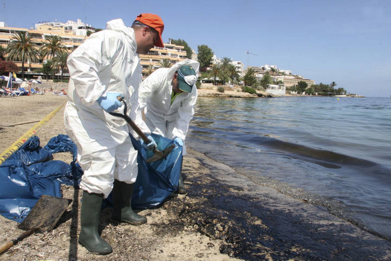 Dos operarios limpian la playa de Figueretas de los vertidos del 'Don Pedro', en julio de 2007.