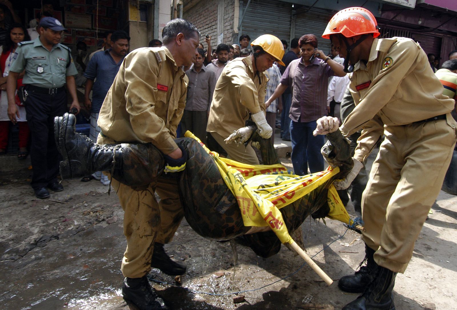 Los bomberos retiran cadáveres de la fosa común hallada en Dacca.