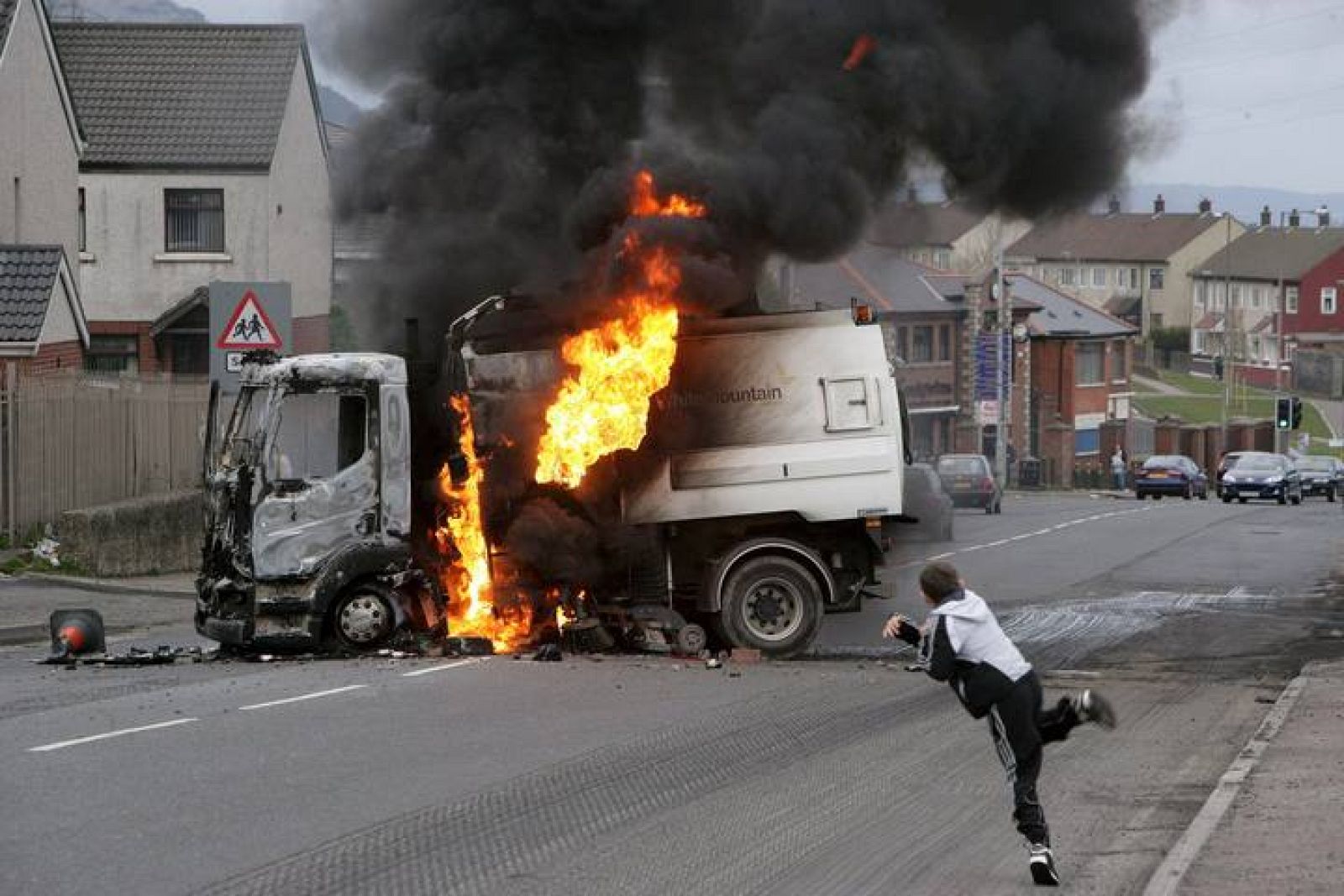 Un niño lanza una piedra contra un camión al que unos desconocidos prendieron fuego después de robarlo al oeste de Belfast, Irlanda del Norte, Reino Unido