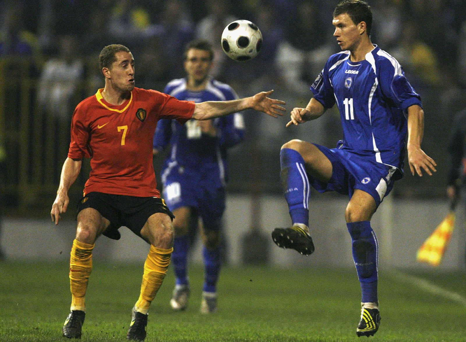 Edin Dzeko de Bosnia disputa u n balón con el belga Gill Swerts.