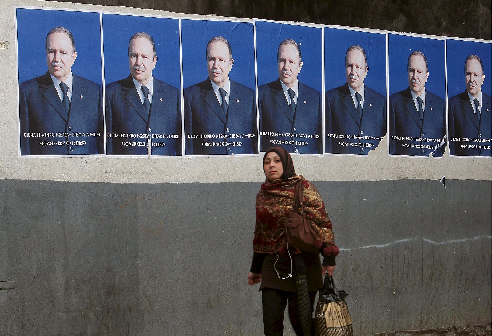 Una mujer pasa junto a los carteles del presidente Abdelaziz Buteflika en Argel.