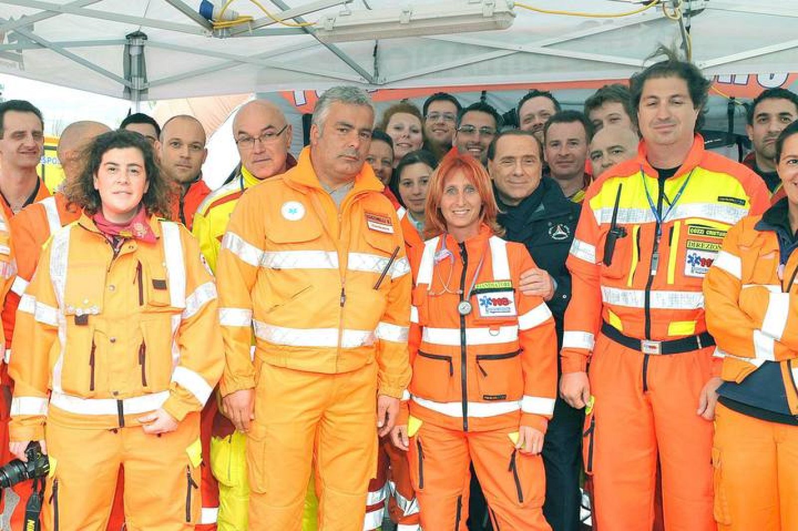 Berlusconi, tras la médico a la que ha cubierto de halagos, posando con el personal de Protección Civil.