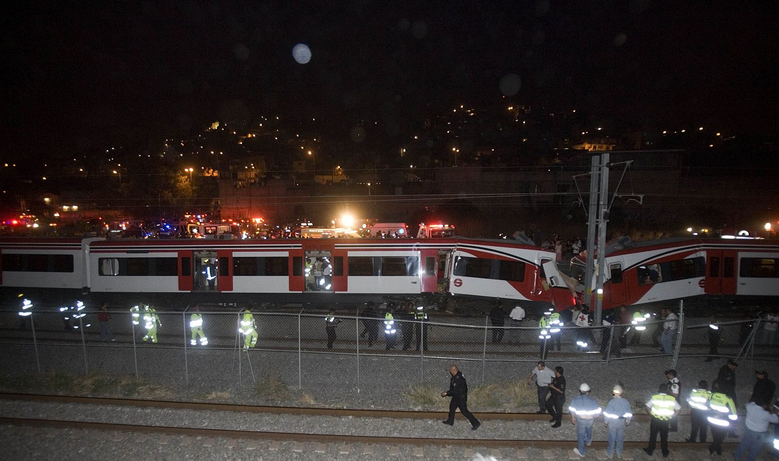 Socorristas evacúan a algunos heridos tras el choque de un convoy del tren suburbano contra otro tren.