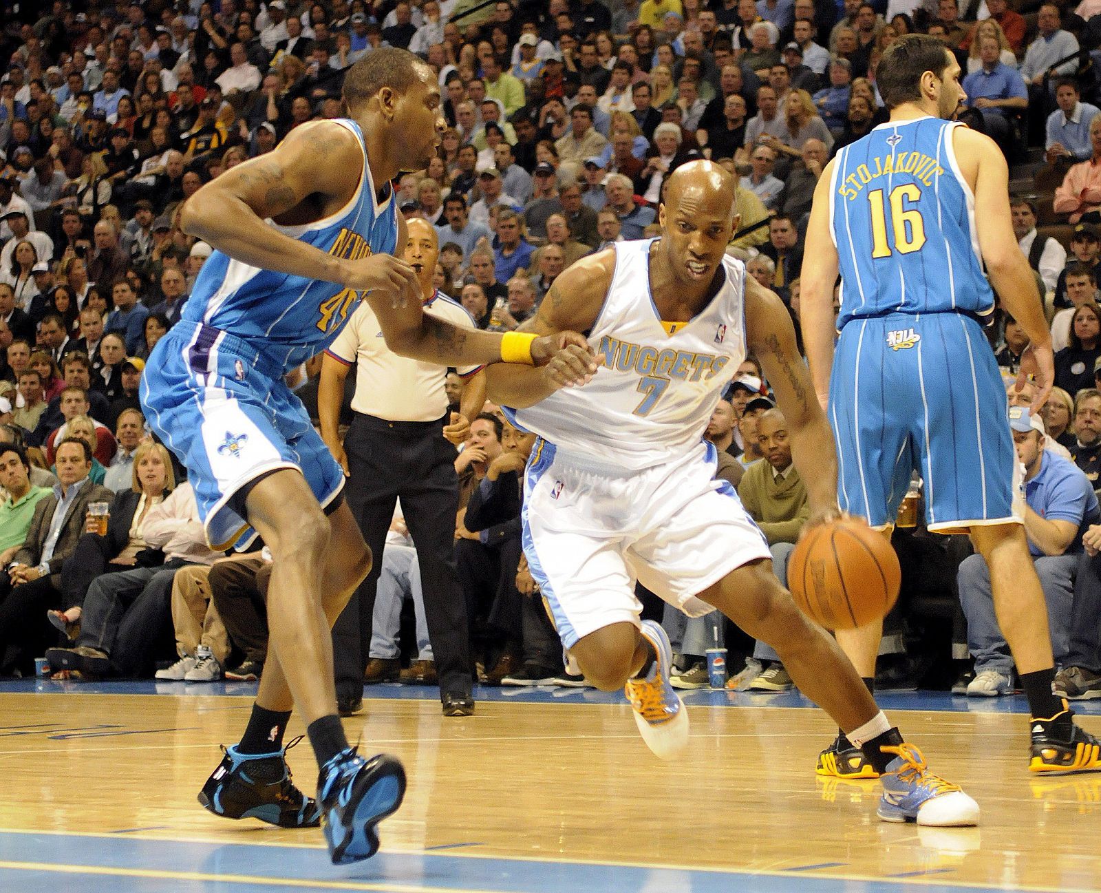 El jugador de los Hornets de Nueva Orleans Rasual Butler (i) domina el balón con la marca de Chauncey Billups (c), de los Nuggets de Denver.