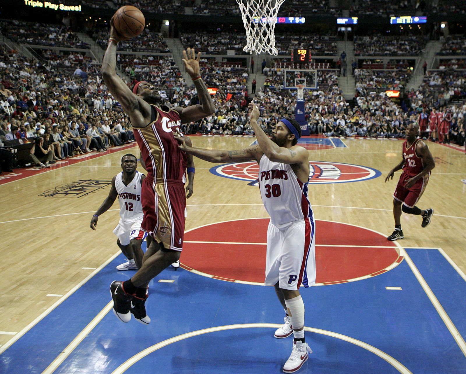 El jugador de los Cavaliers de Cleveland LeBron James (2d) se perfila hacia la cesta con la marca de Will Bynum (i) y Rasheed Wallace (d), de los Pistons de Detroit.