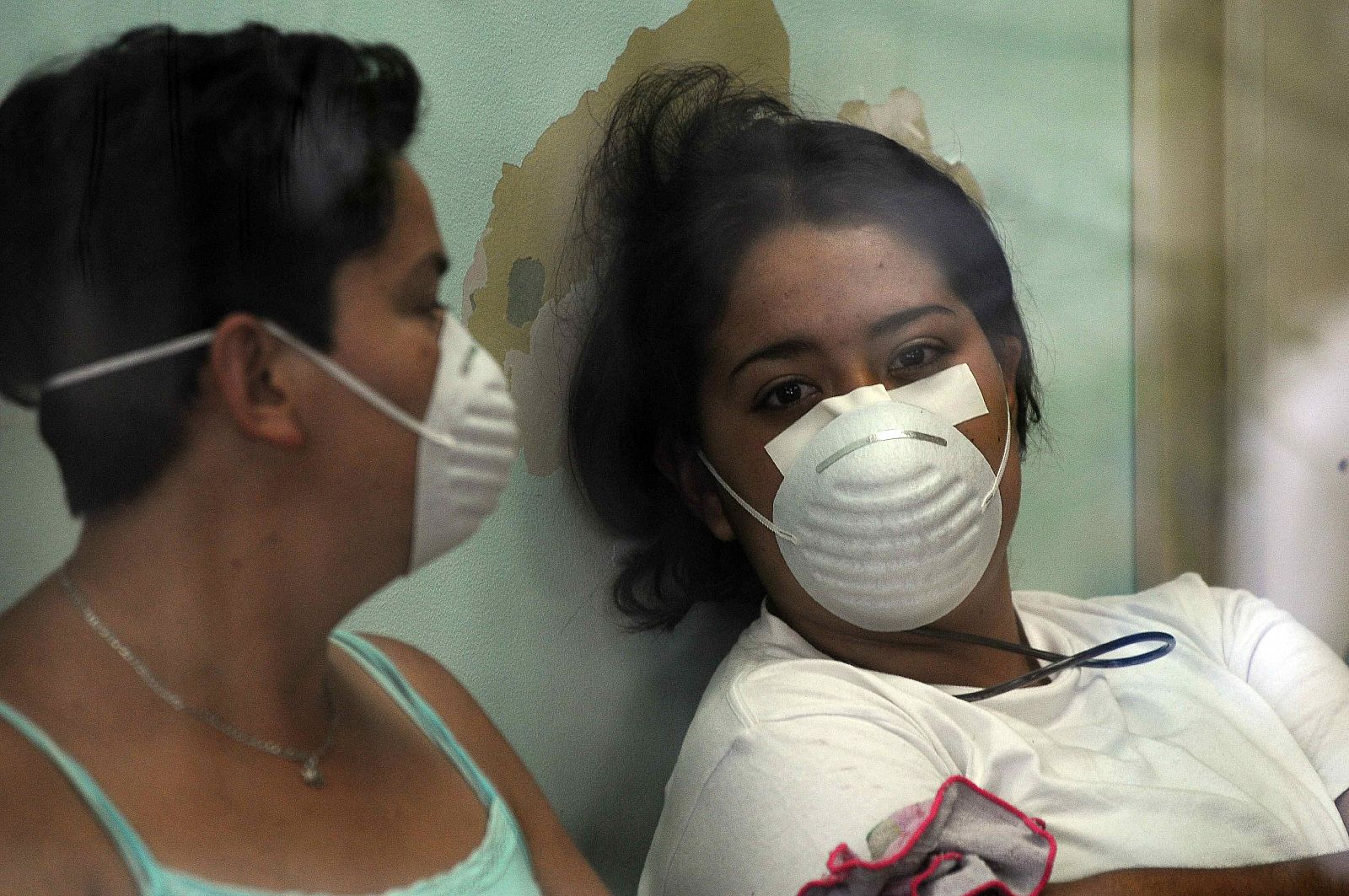 Dos mujeres cubren su rostro con mascarillas ante el brote de gripe.