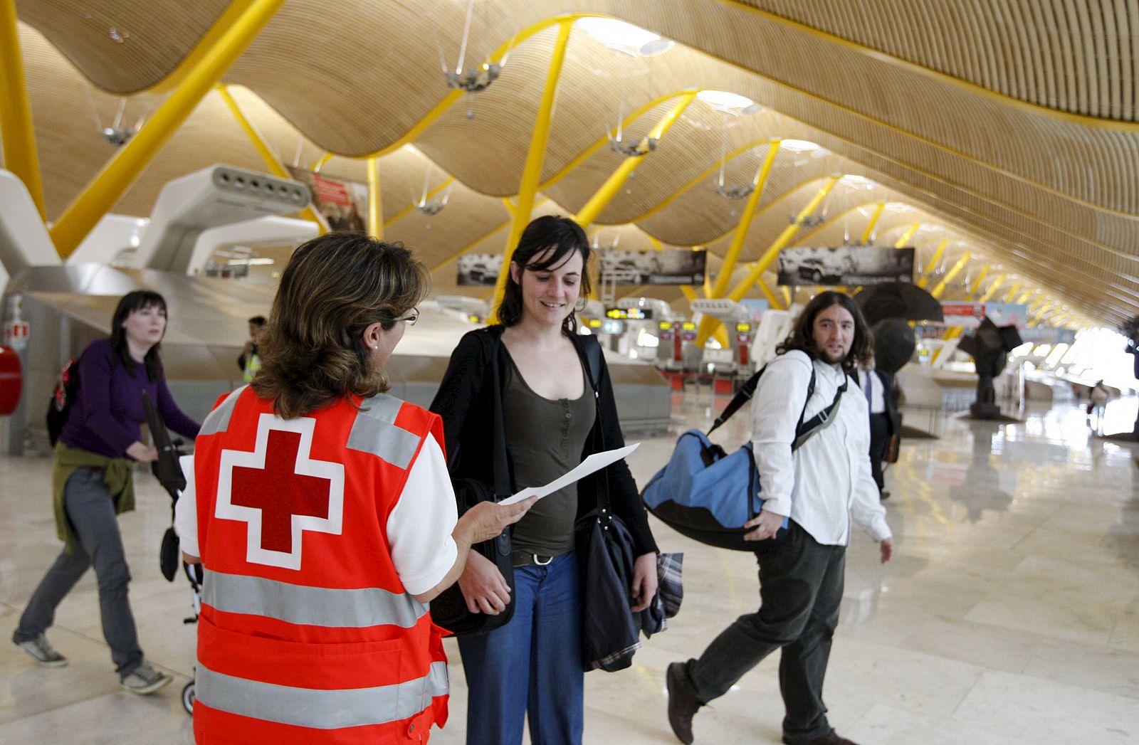 Una volutaria de la Cruz Roja informa a una pasajera sobre la Gripe A en la Terminal 4 del aeropuerto de Barajas.