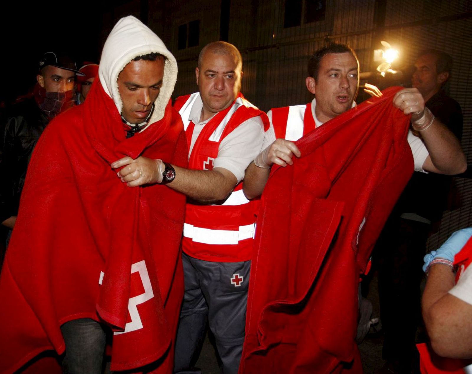 Uno de los 40 inmigrantes que navegaban en dos pateras y que han sido interceptadas por la Guardia Civil en aguas del Cabo de Gata, es ayudado por miembros de la Cruz Roja a su llegada al puerto de Almería.