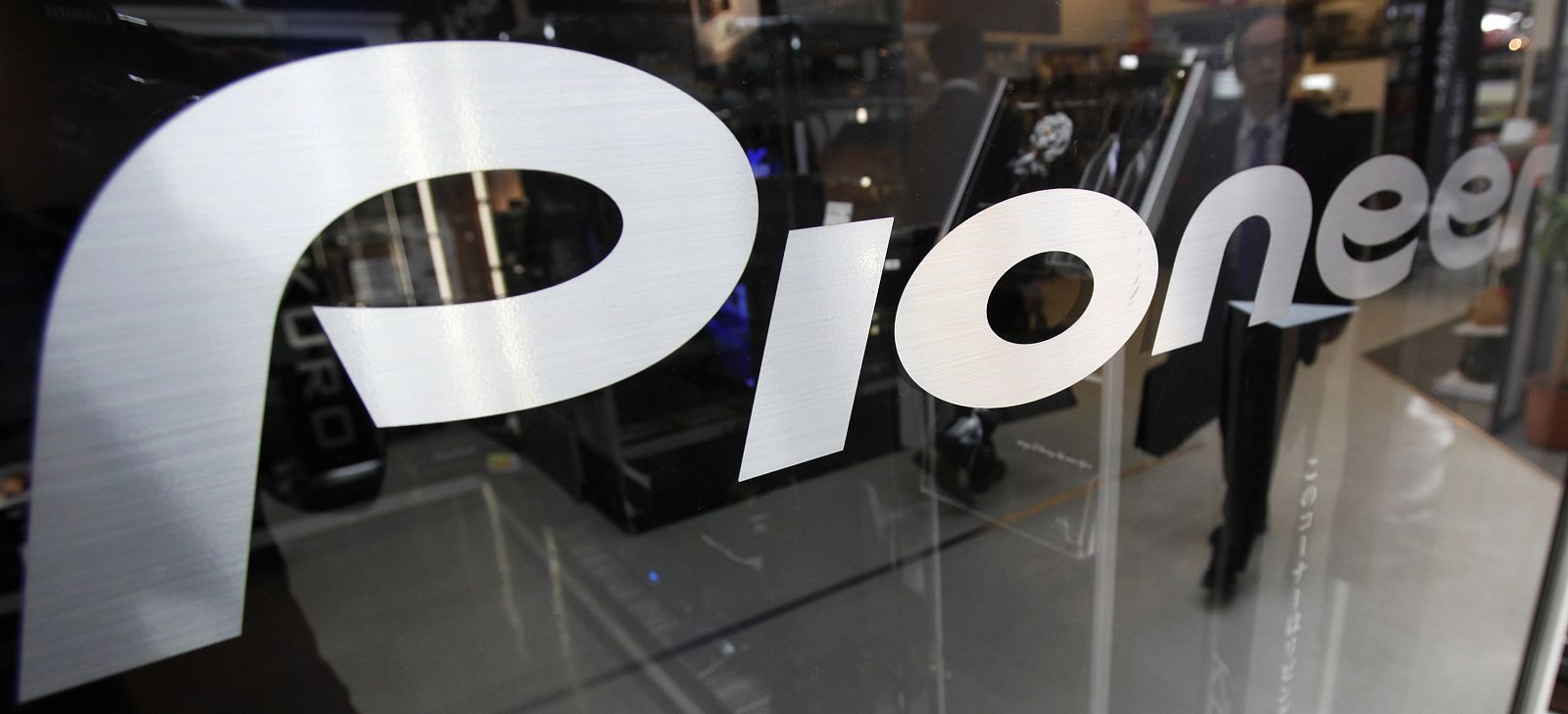 A customer is reflected in a Pioneer Corp sign at an electronics shop in Tokyo