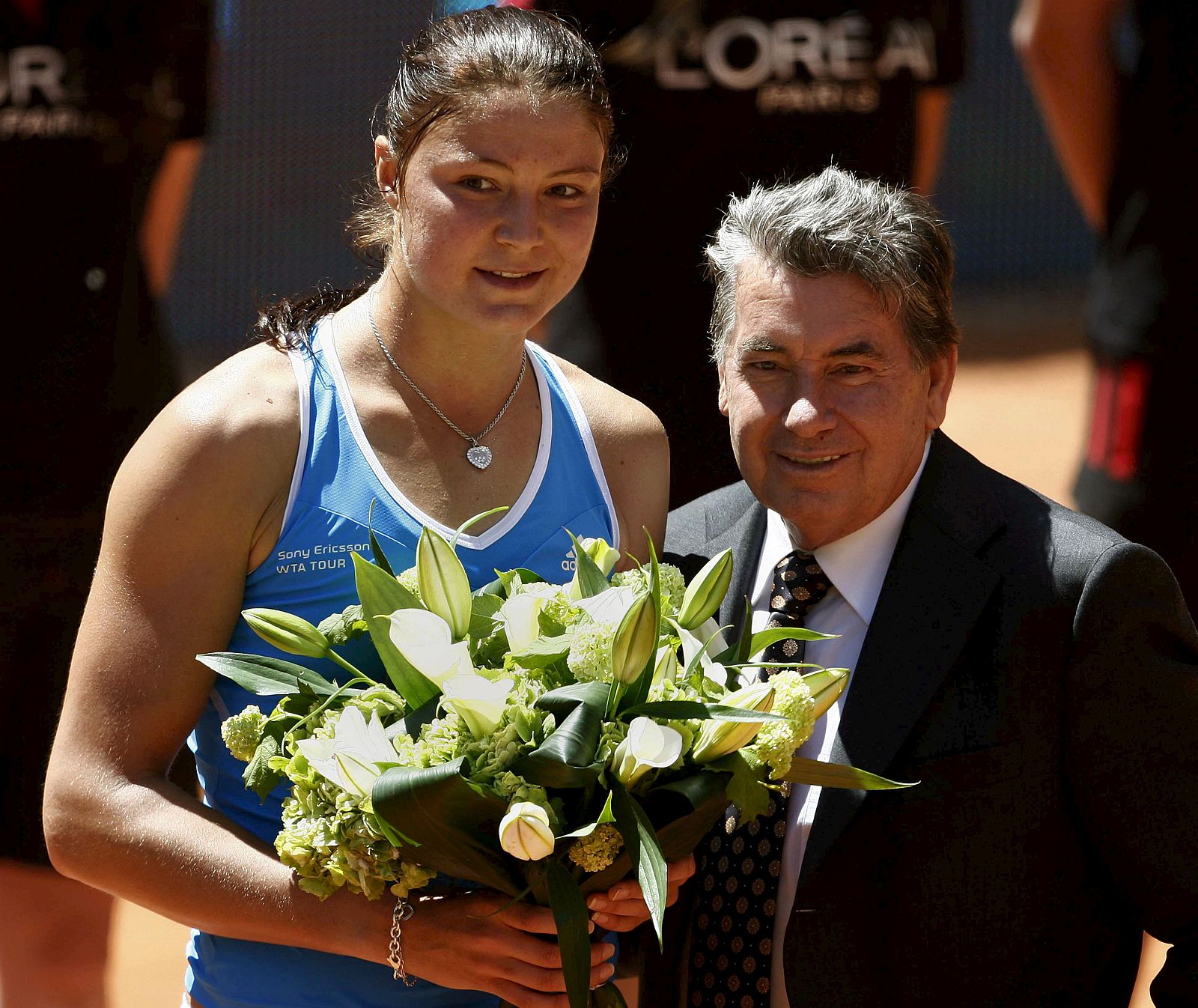 Safina recibe un ramo de flores de manos de Manolo Santana.