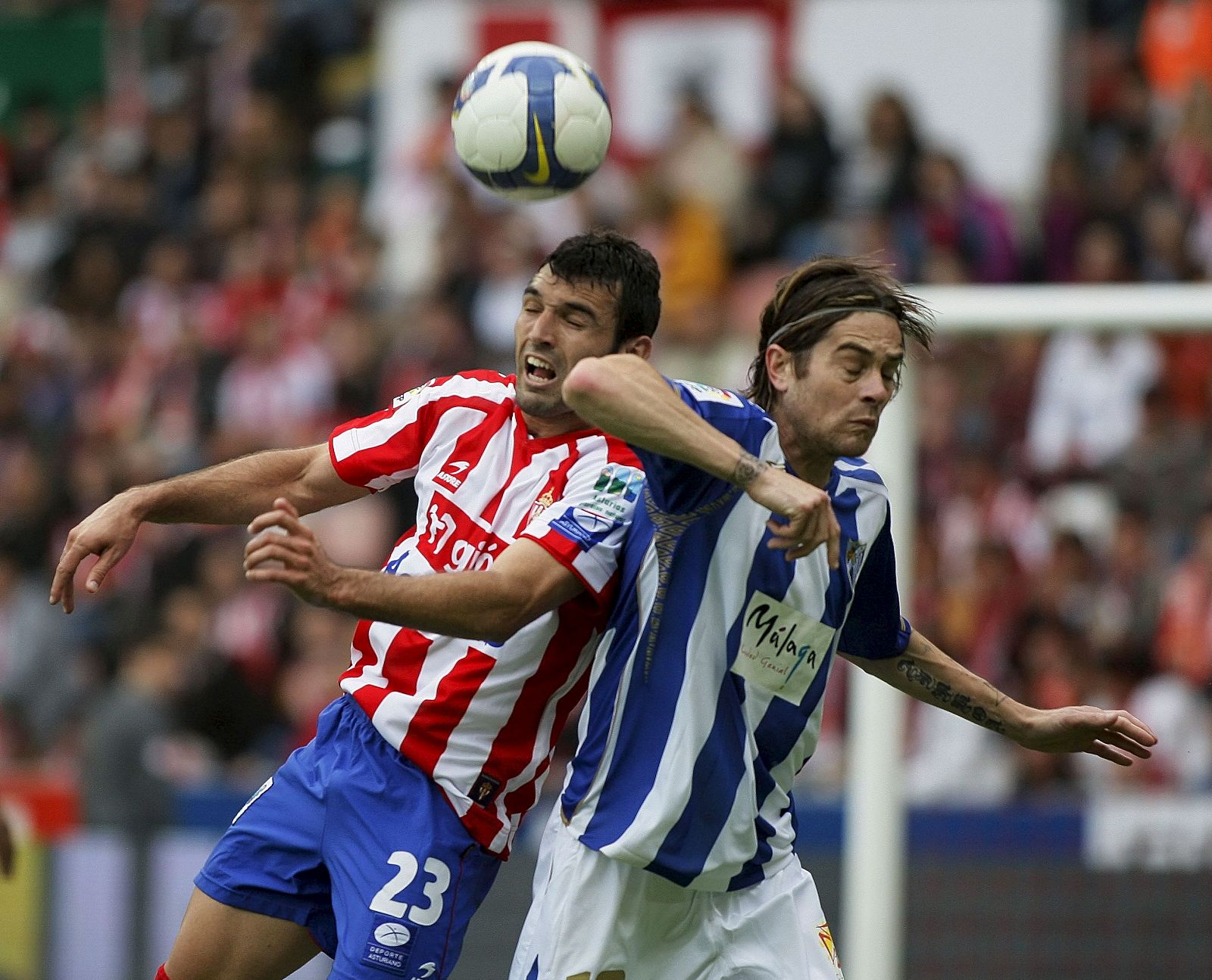 El delantero del Sporting, David Barral (i), lucha la pelota aérea con el centrocampista del Málaga CF, Miguel Ángel Lozano.