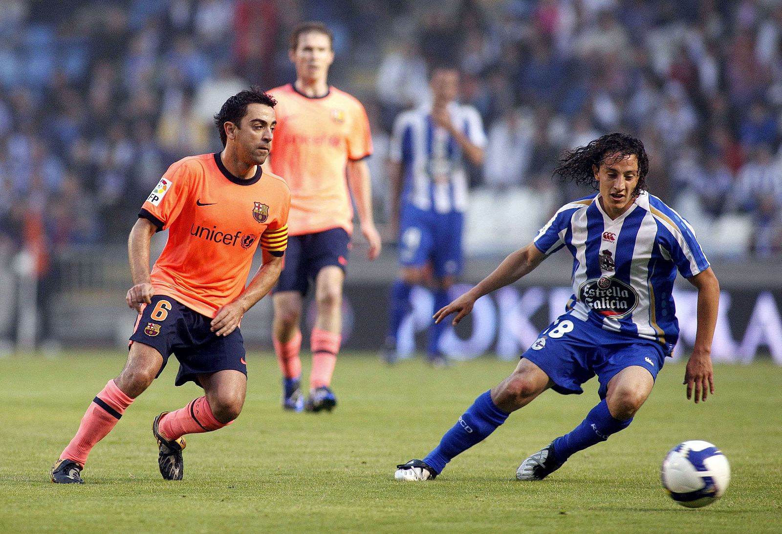 El deportivista Guardado intenta marcharse con el balón delante de Xavi.