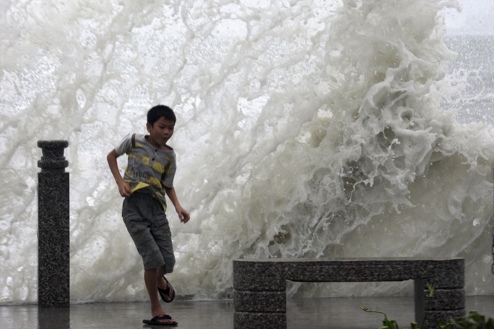 Un niño juega frente a las olas provocadas por la tormenta tropical Goni, en las orillas de Sanya.
