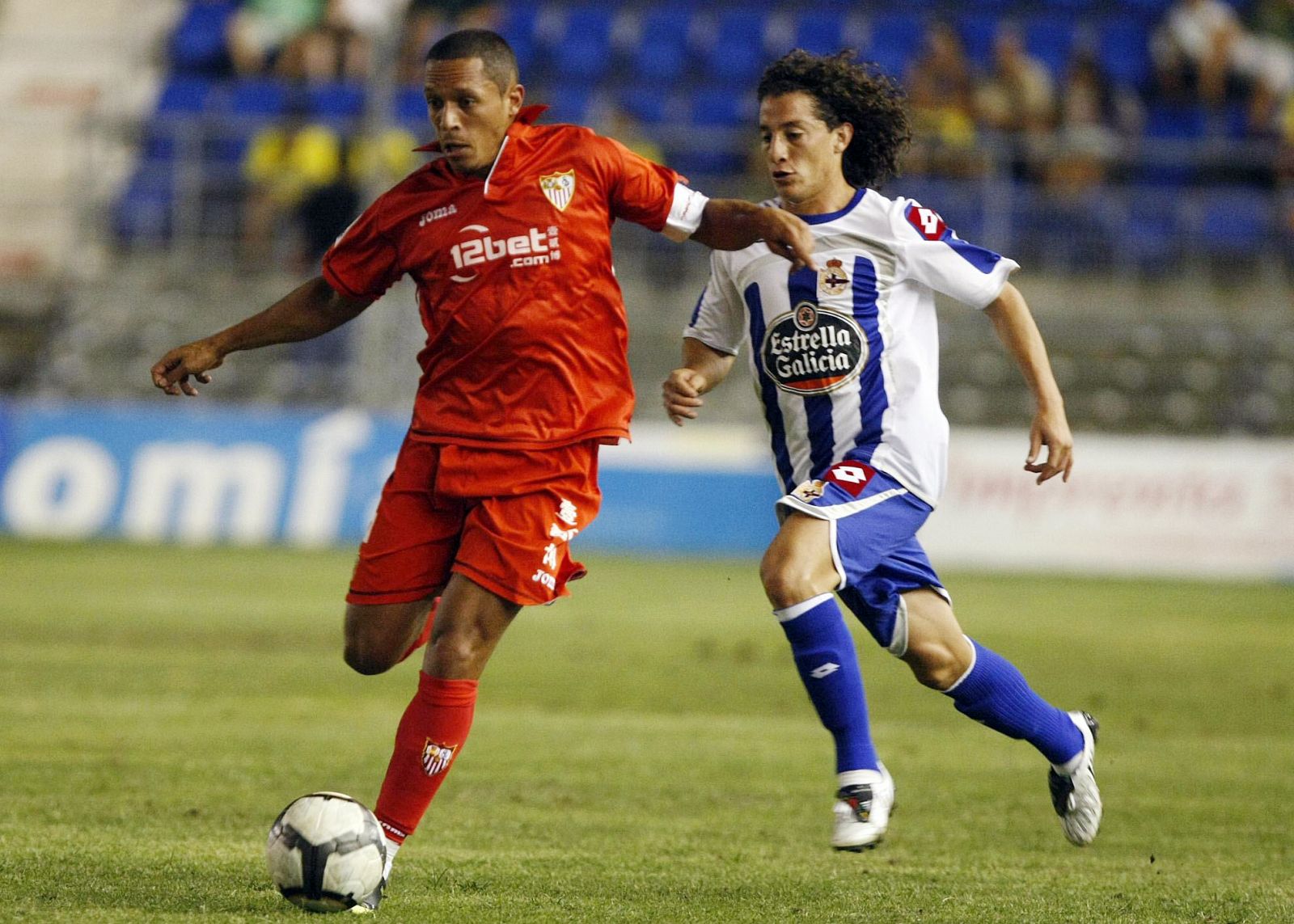 El jugador brasileño del Sevilla Adriano conduce el balón ante el jugador mexicano del Deportivo de la Coruña, Guardado