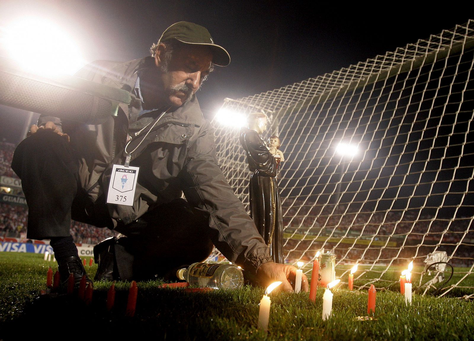 Nereu Correia places candles and a statue of Saint Anthony behind one of the goals in Porto Alegre