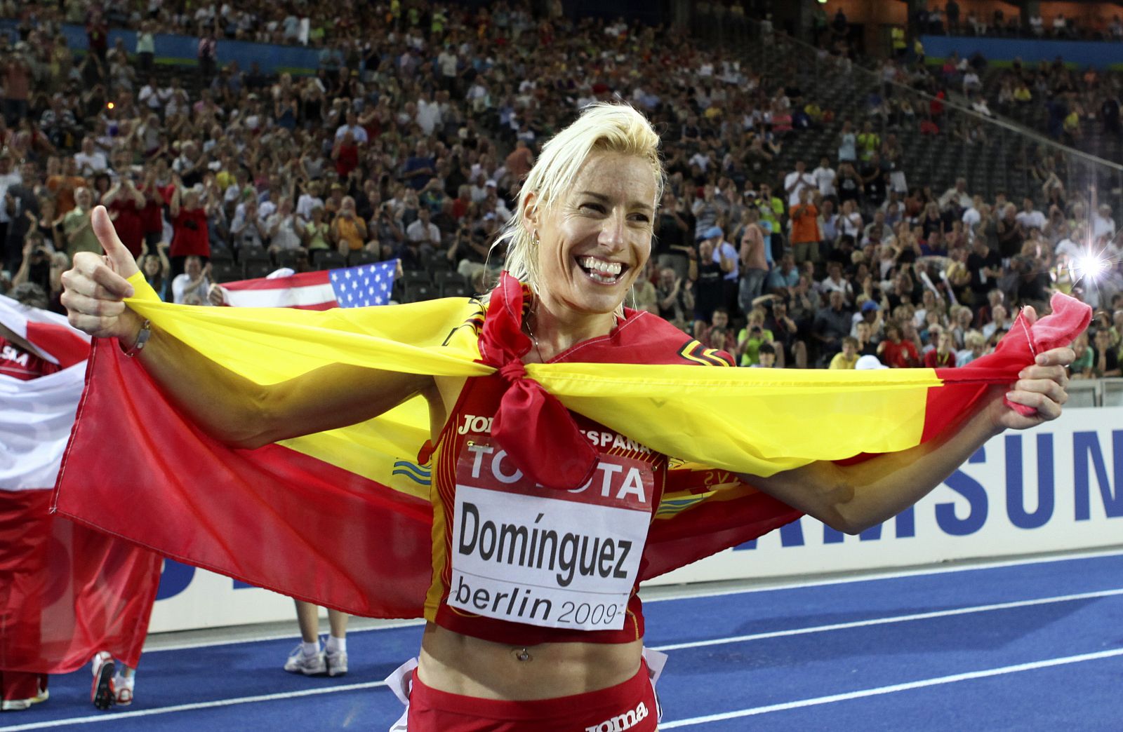 La española Marta Domínguez celebrando el título de campeona del mundo con la bandera de España al cuello.