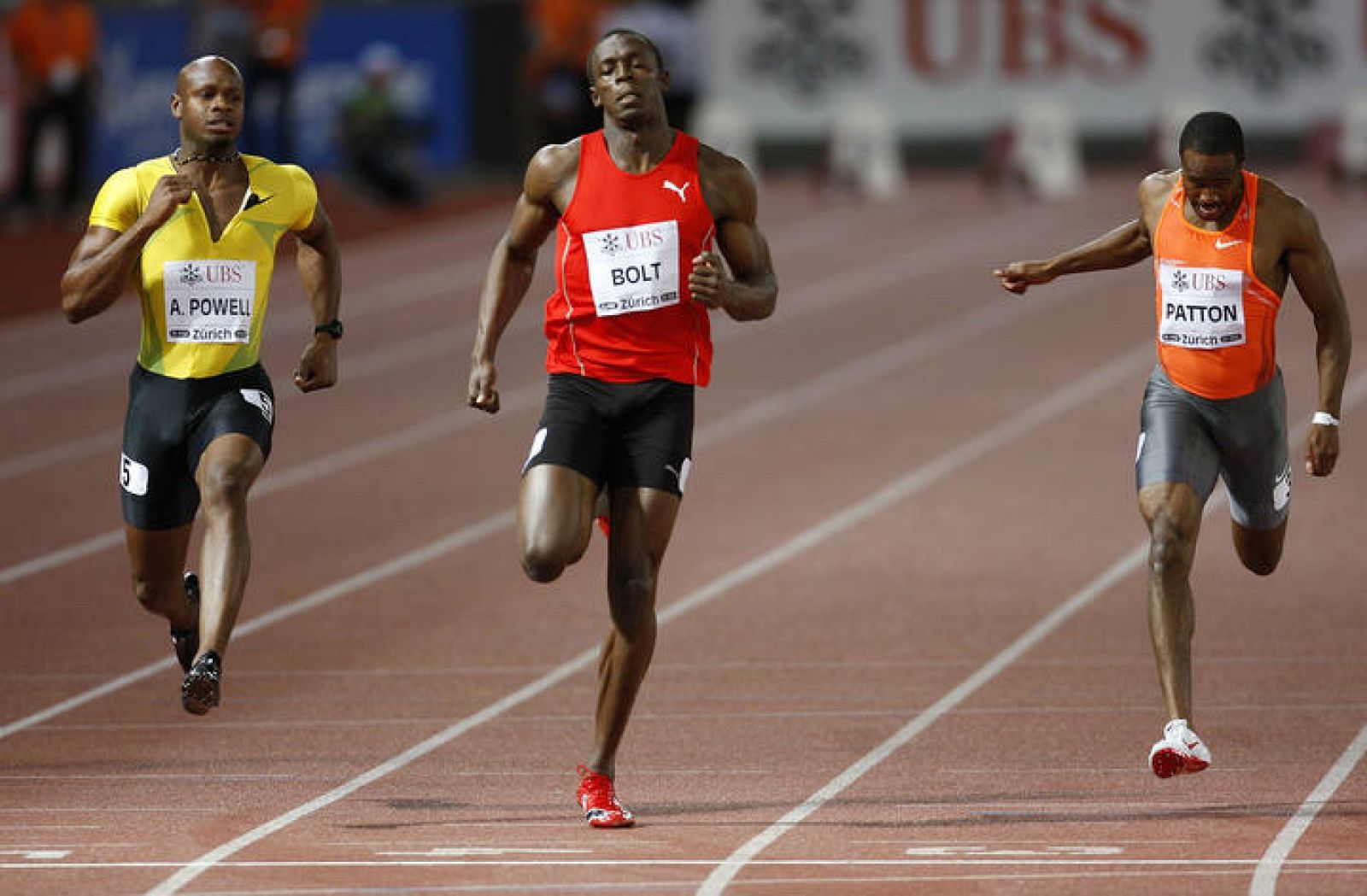 Bolt cruza la meta en Zúrich flanqueado por Asafa Powell y Darvis Patton