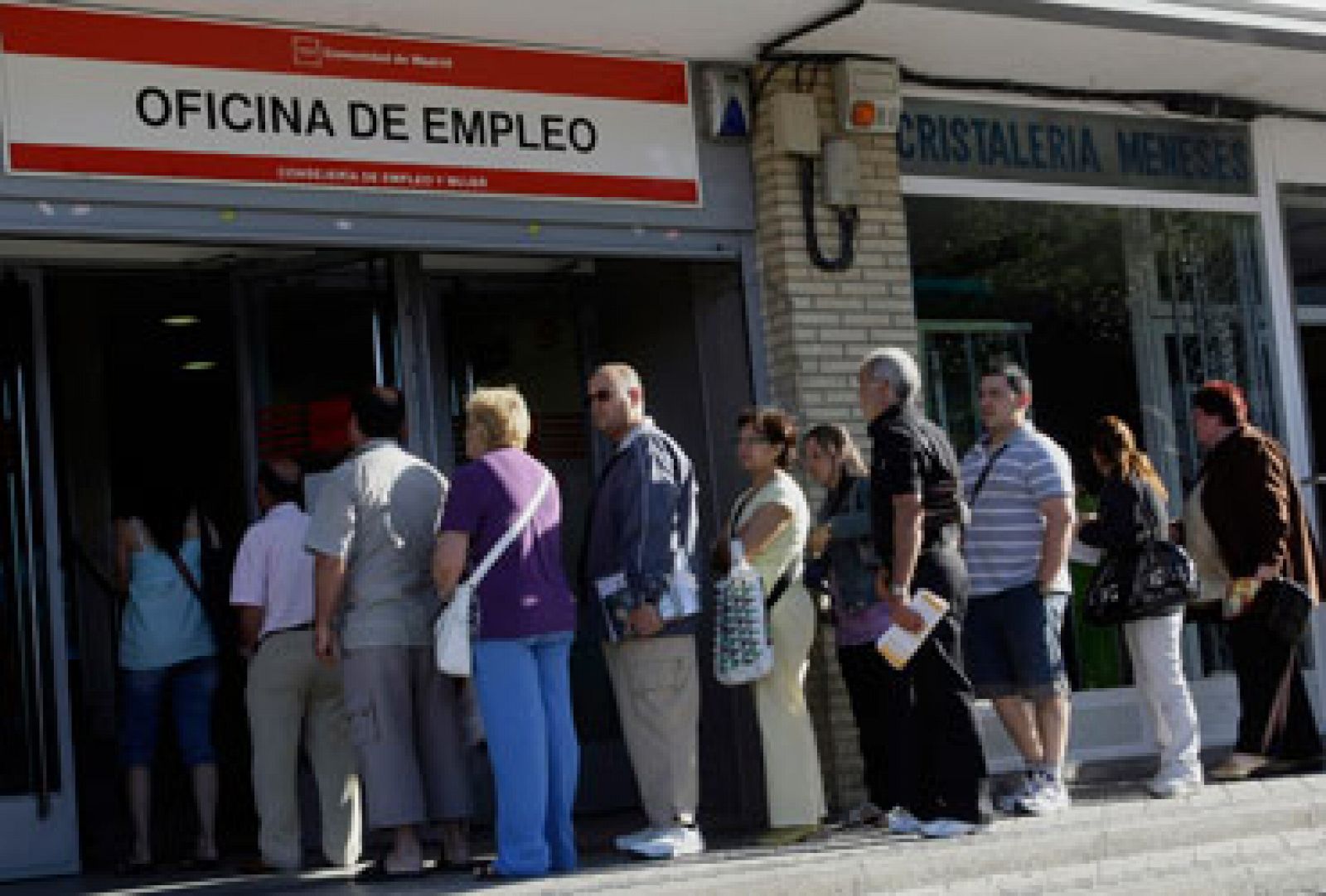 Un grupo de parados hace cola a las puertas de una oficina de empleo.