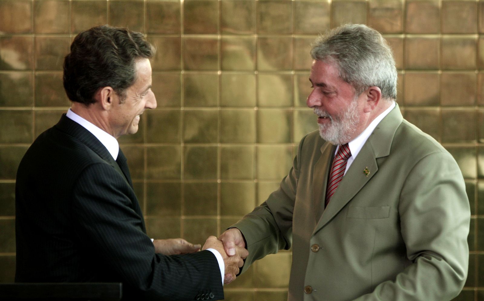 Sarkozy y Lula da Silva se estrechan la mano tras la firma del acuerdo en Brasilia.