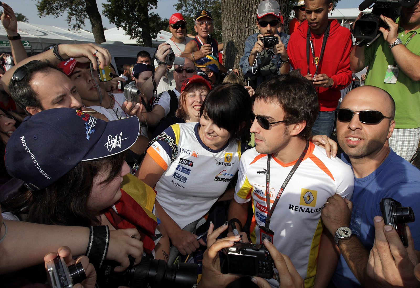 El piloto español de Renault Fernando Alonso firma autógrafos y posa con los aficionados en el circuito de Monza.