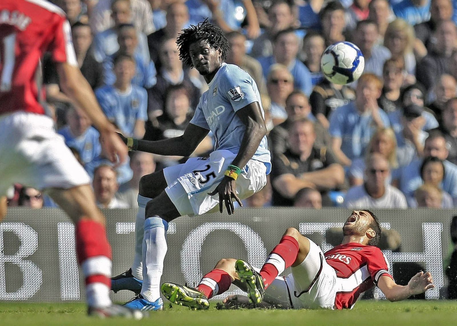 Cesc Fábregas se queja sobre el césped después de que Adebayor le clave los tacos