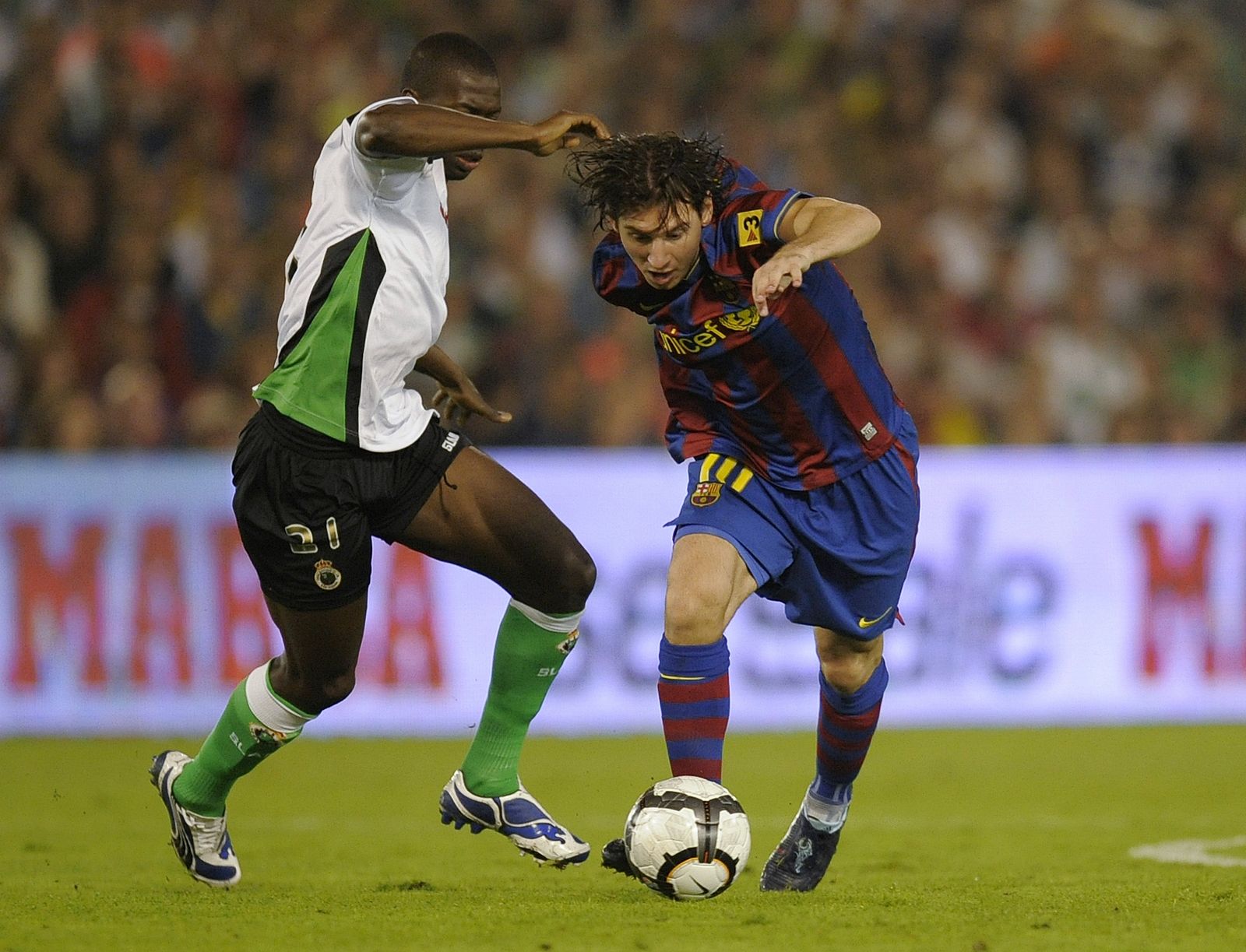 Barcelona's Messi battles for ball with Racing Santander's  Diop during their Spanish First Division soccer match in Santander