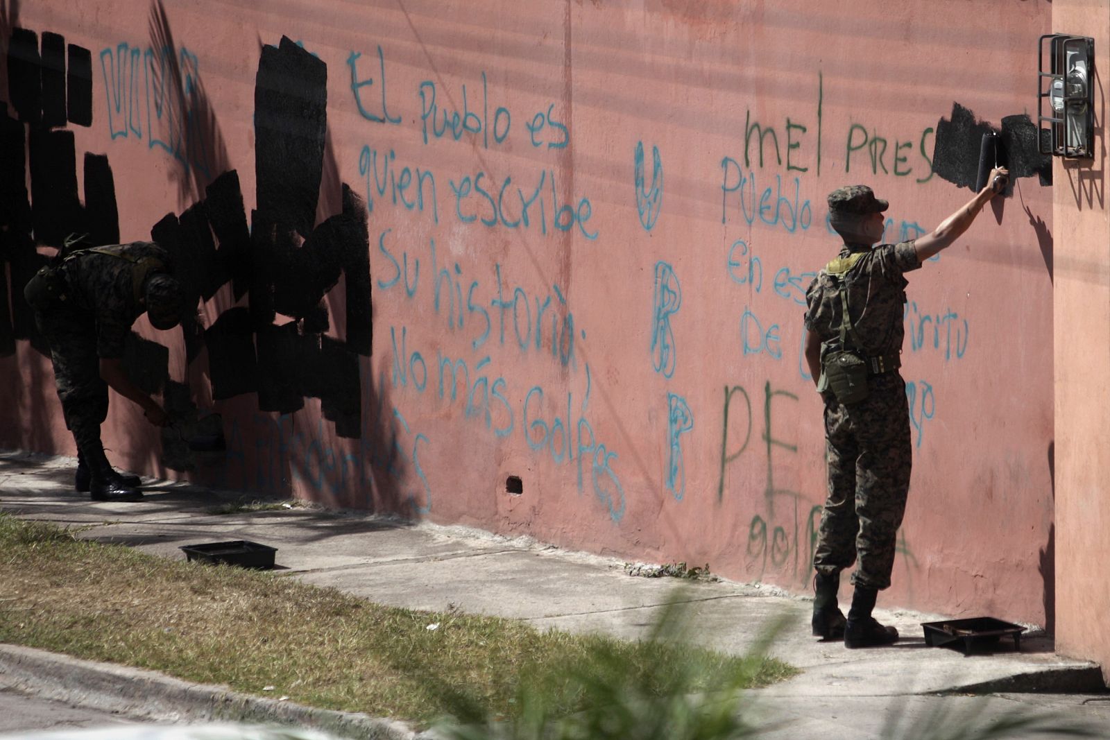 Soldados hondureños borran las pintadas a favor de Zelaya fuera de la embajada brasileña.