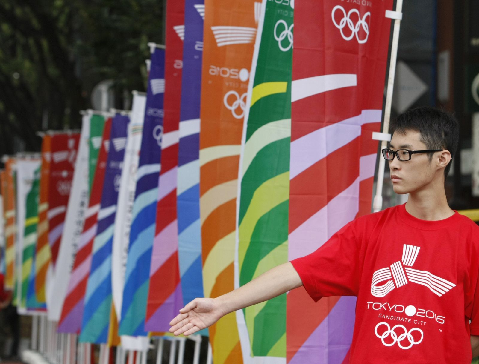 A volunteer stands next to flags during a parade for the Tokyo 2016 Olympic bid, in Tokyo