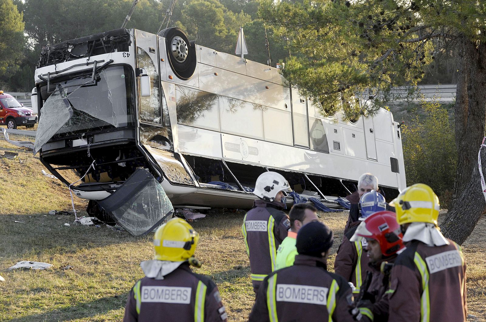 Varios bomberos permanecen junto al autobús que ha volcado en la AP-7, en el término municipal de Bàscara (Girona), c