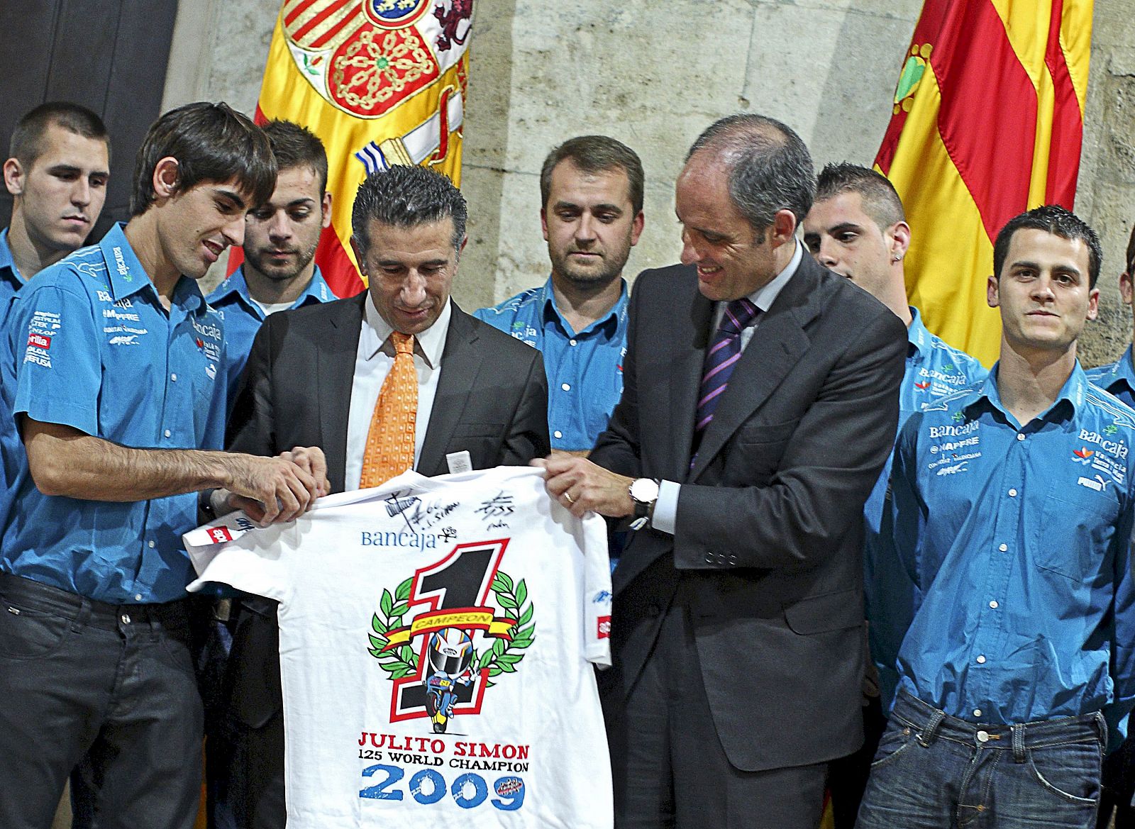 El president de la Generalitat, Francisco Camps, recibe de manos del piloto Julián Simón, campeón del mundo 2009 de 125 cc., y su director de equipo el ex piloto Jorge Martínez "Aspar", una camiseta conmemorativa.