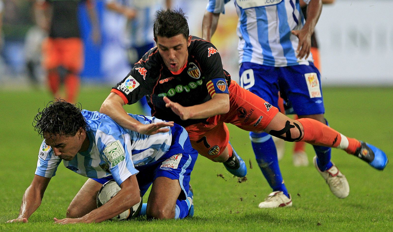 El valencianista David Villa cae sobre el defensa brasileño del Málaga Weligton.