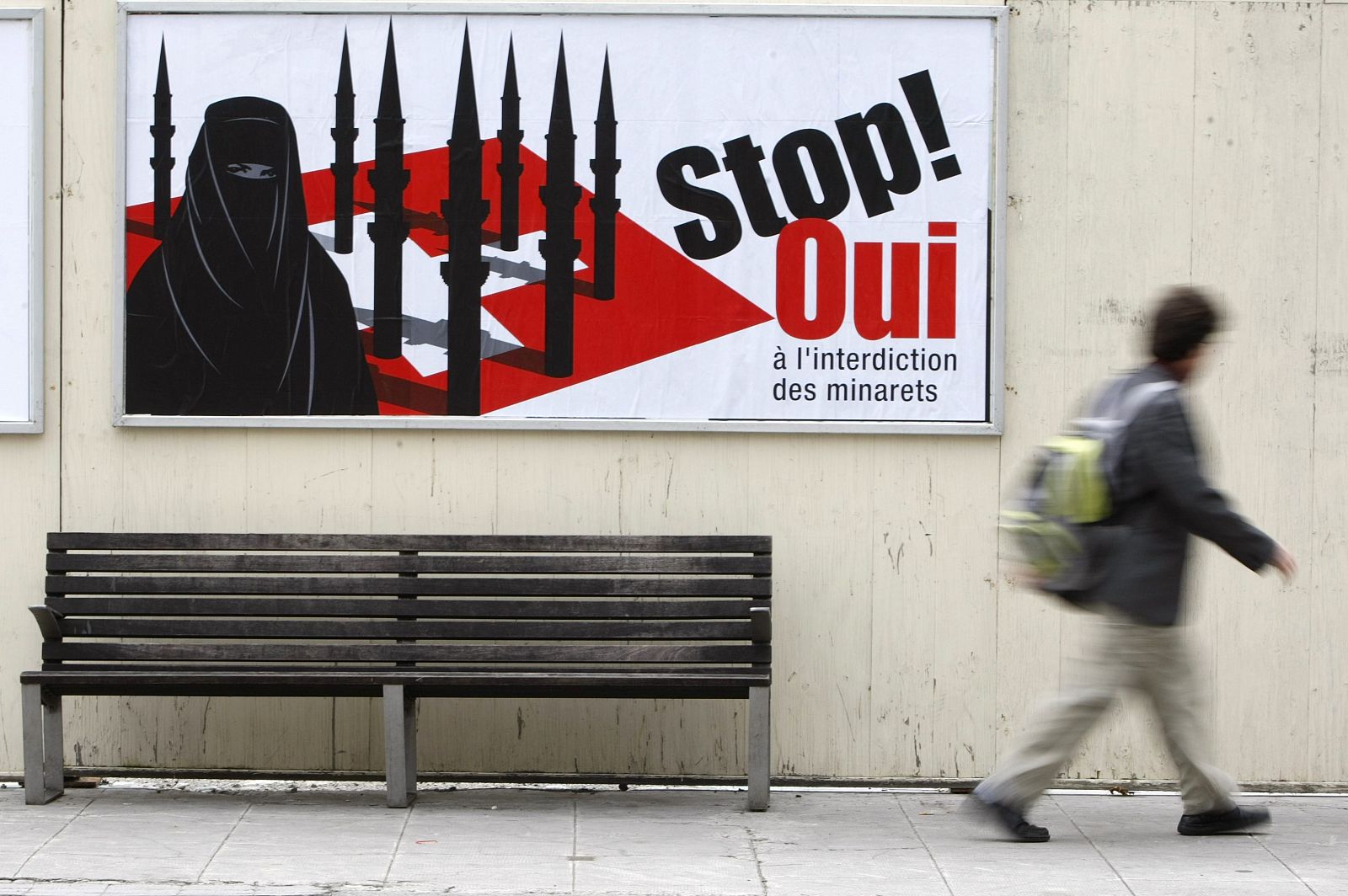 A pedestrian walks past a display advertising the initiative against the construction of new minarets in Switzerland, in Geneva