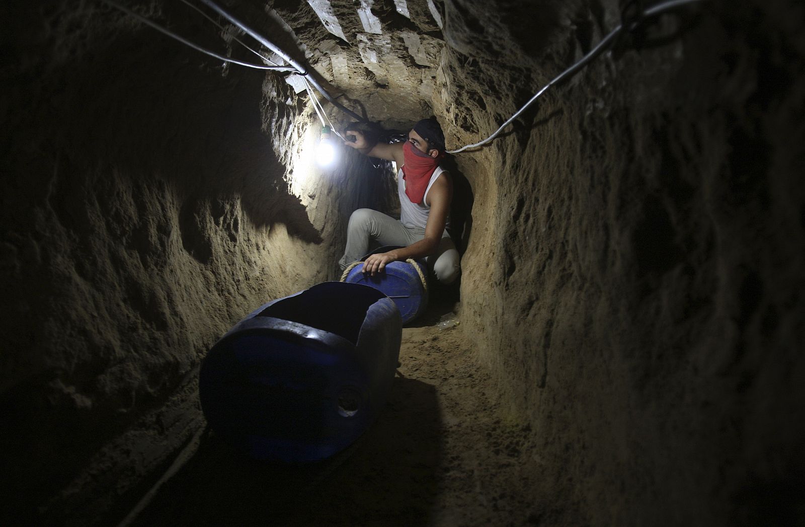 Un palestino enciende la luz en el interior de un túnel entre la frontera de Gaz ay Egipto.
