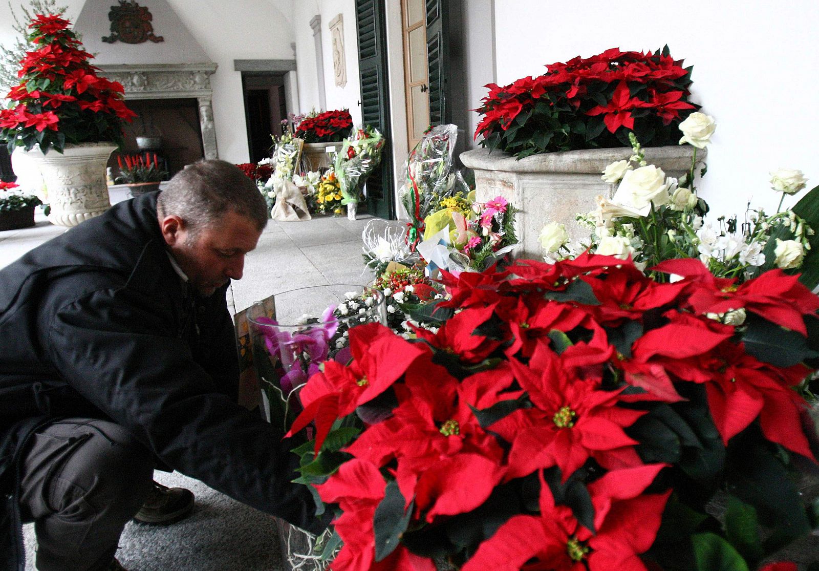 Un hombre coloca un ramo de flores a la entrada de la residencia de Berlusconi.