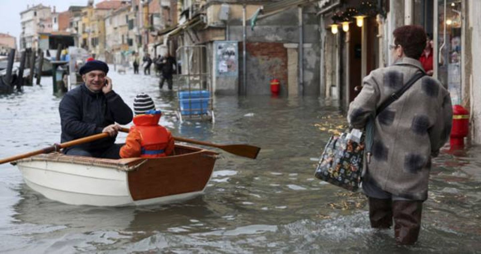 Una mujer con el agua por las rodillas observa a un hombre en un barco