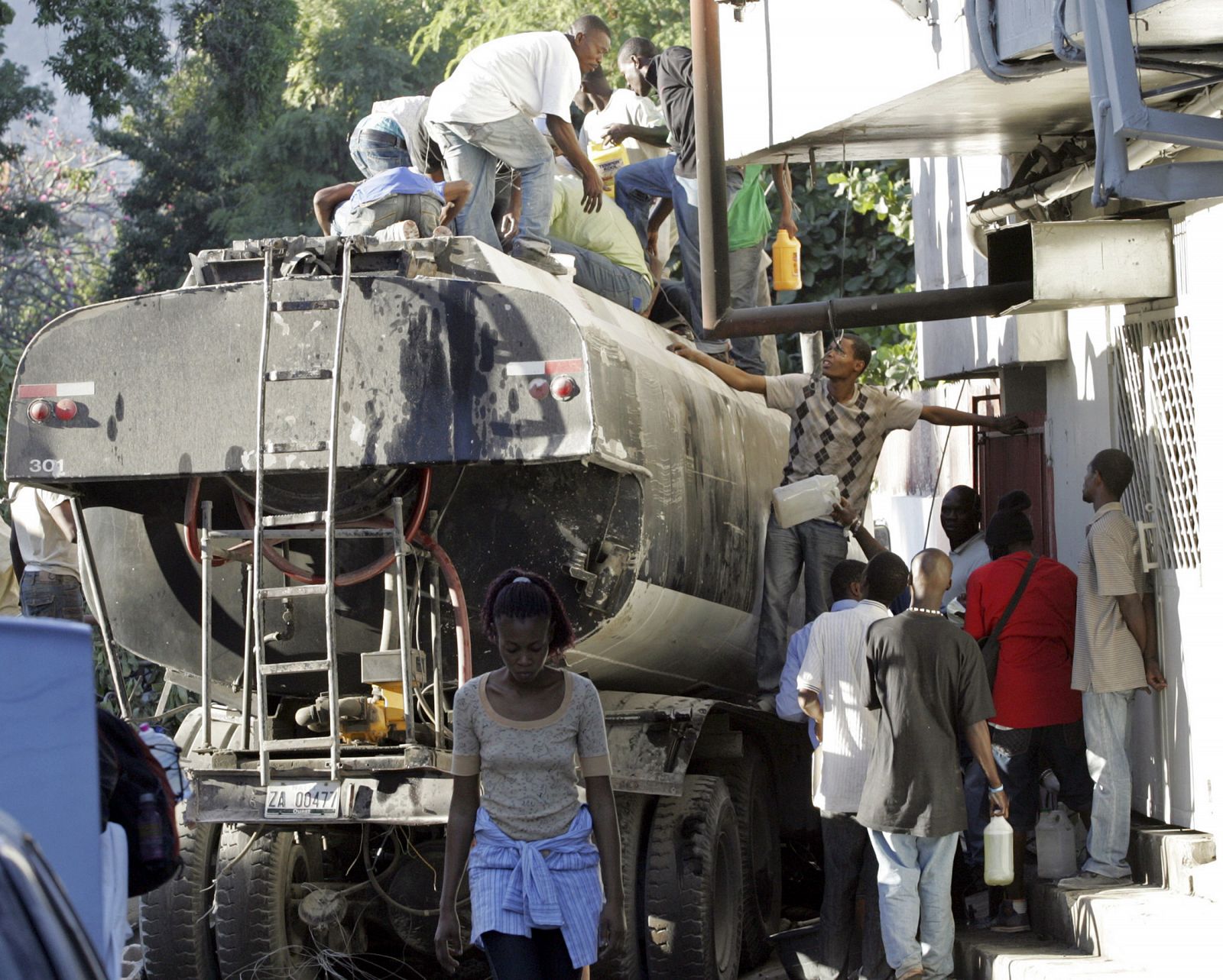 Saqueadores roban gasolina de un tanque roto en Puerto Príncipe.