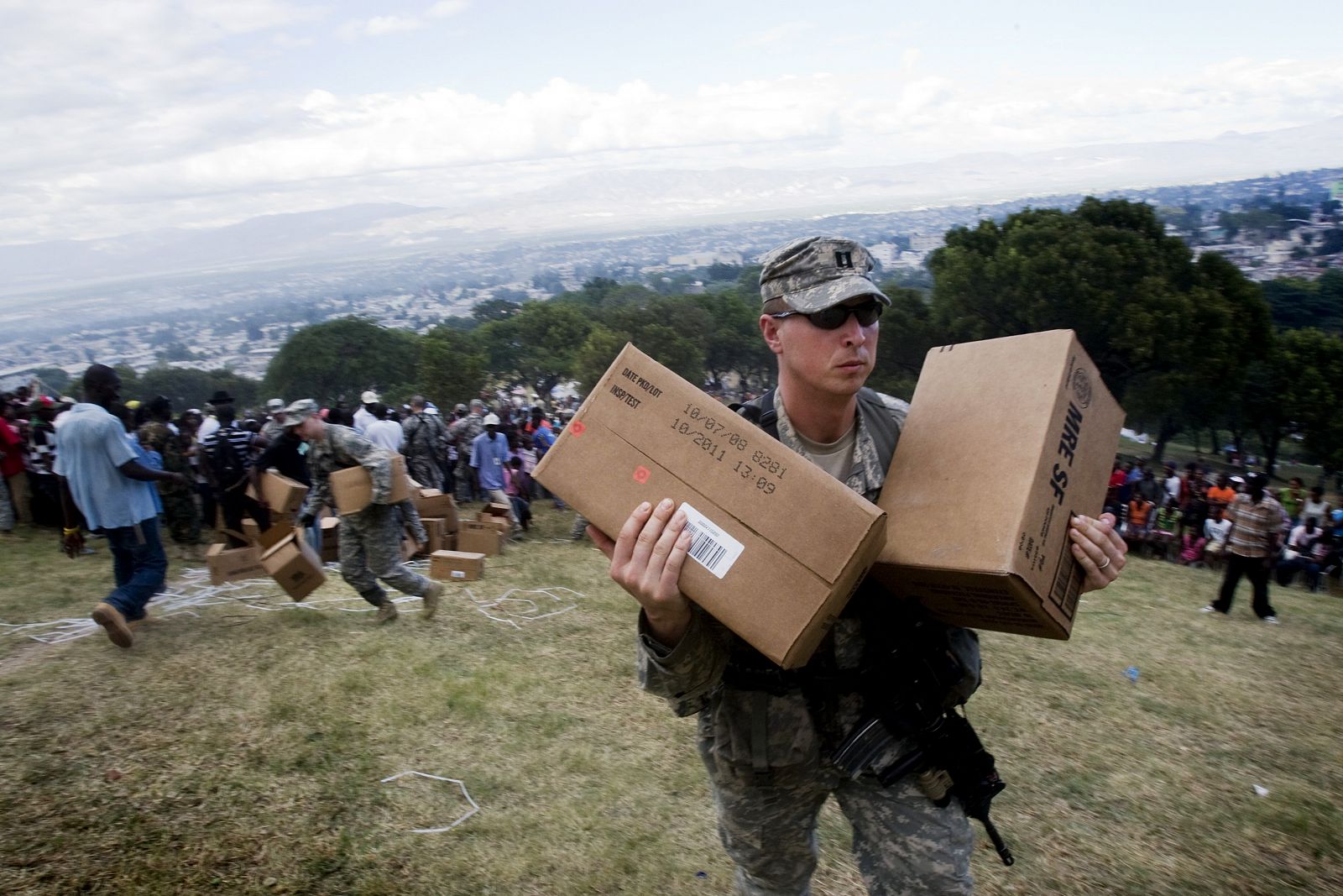 Un marine llega una caja con ayuda en un campamento improvisado en un campo de golf de Puerto Príncipe.