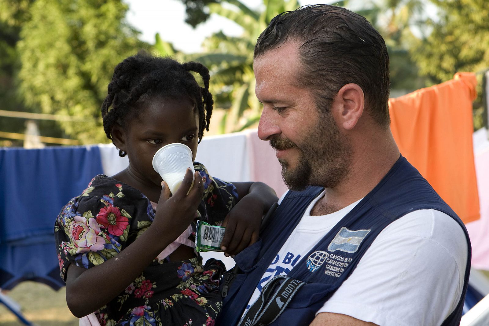 Una niña, junto a un cooperante argentino en Haití.